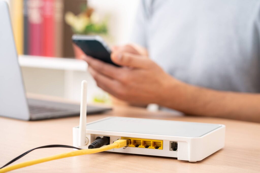 Man using multiple devices with broadband router in background